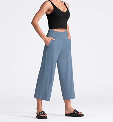 As calças de ioga feminino da ginástica com bolsos e barriga de controle de altura da cintura na colheita
