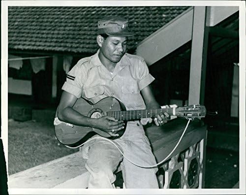 Foto vintage de um do guarda -costas do coronel Simbolen39, fica tocando violão.
